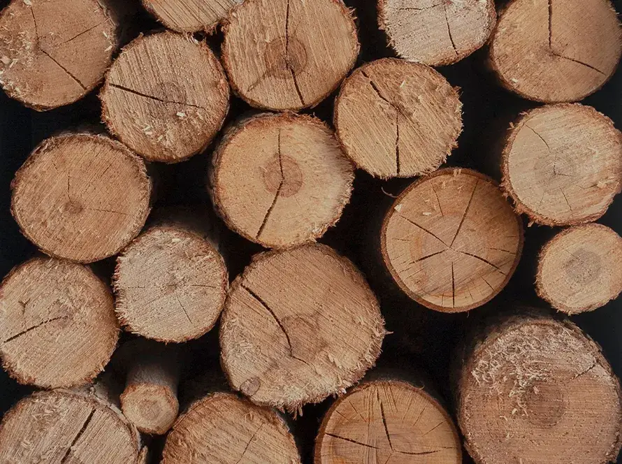 Piquets de bois ronds et refendus empilés, idéaux pour les clôtures et décorations.